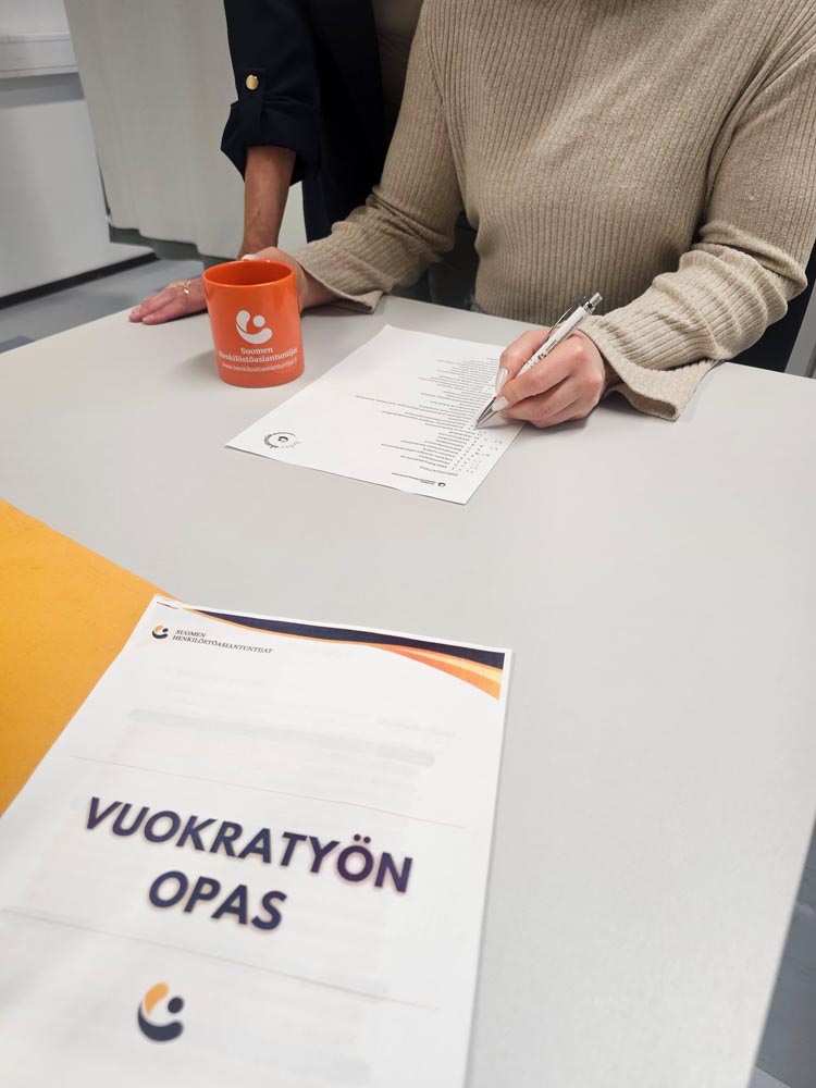 Asiantuntija allekirjoittaa vuokratyön oppaan neuvottelupöydässä.